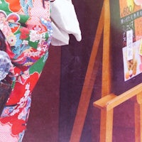 a woman in kimono standing next to an easel
